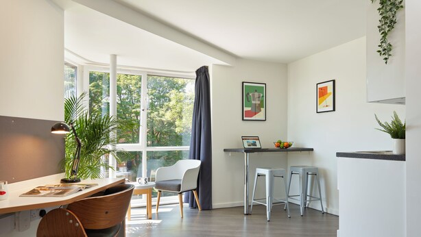 A modern kitchen with a dining area, a large window, and a plant. - For Students Only - Modern Accommodation in Leeds City Centre (Leeds)