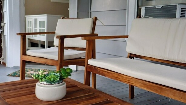 A wooden bench and chair with white cushions in a room with a window and an air conditioning unit. - Cozy Dog-Friendly Boho Duplex (Lakewood)