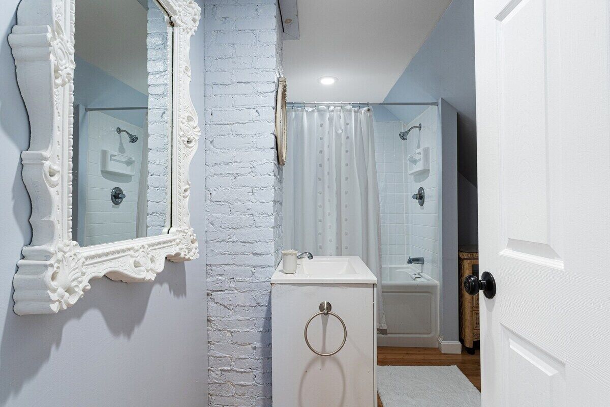 A bathroom with a white vanity, a large mirror, a shower, and a bathtub.
