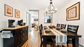 Un comedor con mesa de madera, sillas, una lámpara de araña y obras de arte en las paredes.