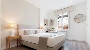 A modern bedroom with a large bed, bedside tables, a mirror, and a view of the outside. - Genteel Home Abada Terrace (Madrid)