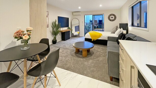 Ein modernes Wohnzimmer mit Essbereich, einer Couch, einem Couchtisch und einer Küchenzeile.