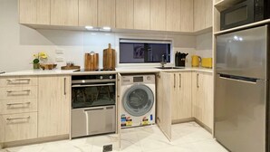 Eine kleine Küche mit Holzausstattung, einem Einbauofen, einer Waschmaschine und einem Kühlschrank.