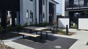 Edificio moderno con un patio que tiene una mesa de picnic y pequeñas plantas.