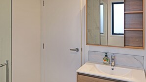 Un baño con un lavamanos blanco, un espejo y una botella de jabón para manos.