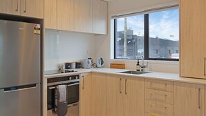 Una cocina moderna con un refrigerador de acero inoxidable, horno empotrado, ventana con vistas a la ciudad y armarios de madera.