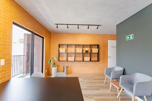Un espace de bureau moderne avec un mur en briques, une grande fenêtre, une table de conférence et deux chaises grises.