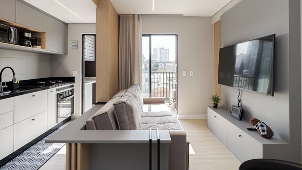 Un appartement moderne doté d’une cuisine, d’un canapé, d’une télévision et d’un balcon offrant une vue sur la ville.