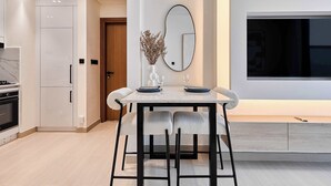 Une cuisine moderne avec des meubles blancs, un plan de travail en marbre et un coin repas comprenant une table et des chaises.