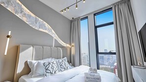 A modern hotel room with a large bed, a city view, and a unique ceiling design.