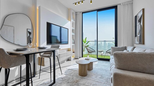 A modern living room with a dining area, a flat-screen TV, and a large balcony with a city view.