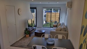 Un salon moderne comprenant un coin repas, un ensemble de canapés, une table basse et un téléviseur.