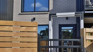Un bâtiment moderne à deux étages, doté d’une façade en briques, d’une grande fenêtre et d’un portail en bois.