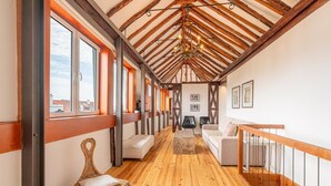 A spacious loft-style room with high ceilings, exposed wooden beams, and large windows. - GuestReady - Alfama Terrace B1 (Lisbon)