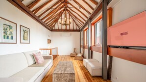 A spacious room with a high wooden ceiling, a large window, and a flat-screen TV on the wall. - GuestReady - Alfama Terrace B1 (Lisbon)