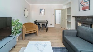 Una sala de estar moderna con televisor de pantalla plana, un sofá, una mesa de centro y un comedor con mesa y sillas.
