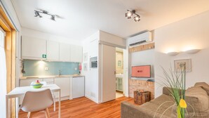 A compact living space with a kitchenette, a dining area, a TV, and a sofa. - GuestReady - Alfama Terrace H (Lisbon)