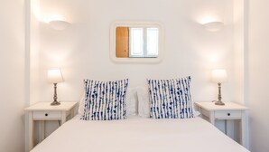 A bedroom with a large bed, two bedside tables with lamps, a window with a view, and a small mirror above the bed. - GuestReady - Alfama Terrace H (Lisbon)