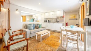 A compact living space with a sofa, chairs, a dining table, a kitchen area, and a TV. - GuestReady - Alfama Terrace G (Lisbon)