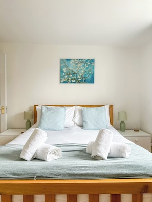 Una habitación de hotel con una cama, almohadas, un cuadro y dos lámparas de noche.