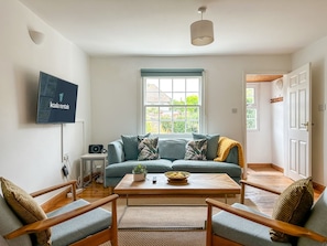A living room with a sofa, a coffee table, and a television mounted on the wall.