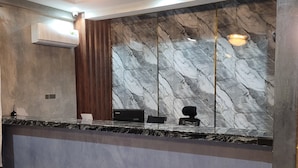 A reception area with a marble wall, a reception desk, and a chandelier. - JR KISASA HOTEL (Dodoma)