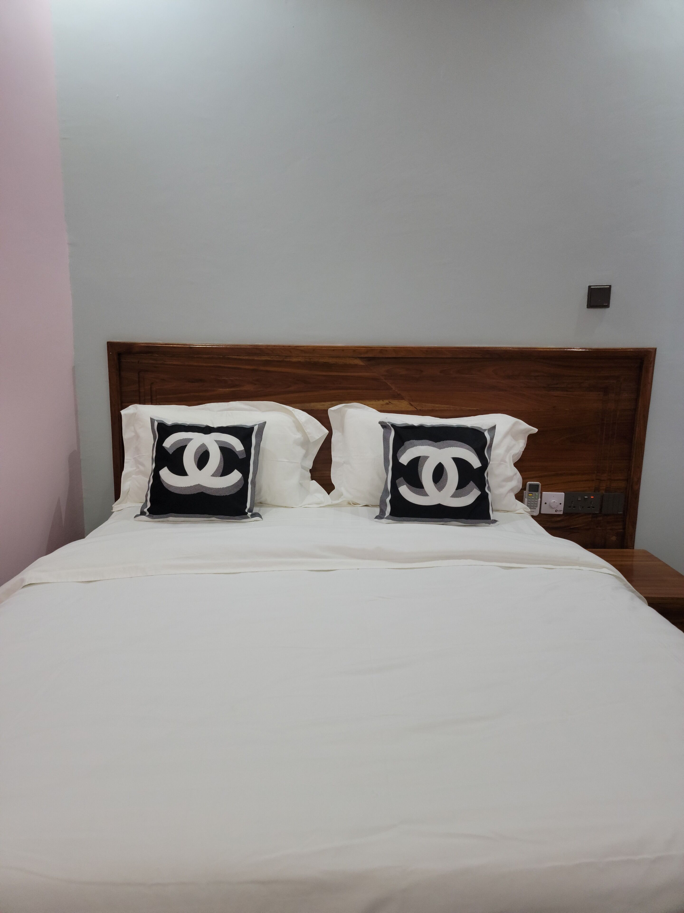 A bed with white bedding and two pillows featuring a large 'C' logo.
