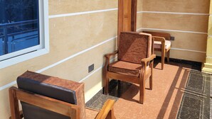 A room with a large window, wooden chairs, a wooden door, and a patterned floor. - JR KISASA HOTEL (Dodoma)