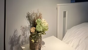 A bedside table with a small vase of dried flowers and a lamp. - Collection R 2 Bellas Artes (Santiago)