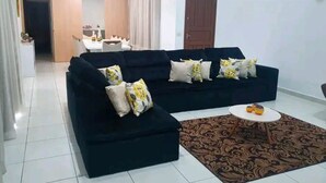 A living room with a black sofa set, a patterned rug, and a small round table. - House with Heated Pool - Perequê-Açu - UBATUBA - SP (Perequê-Acu Ubatuba)