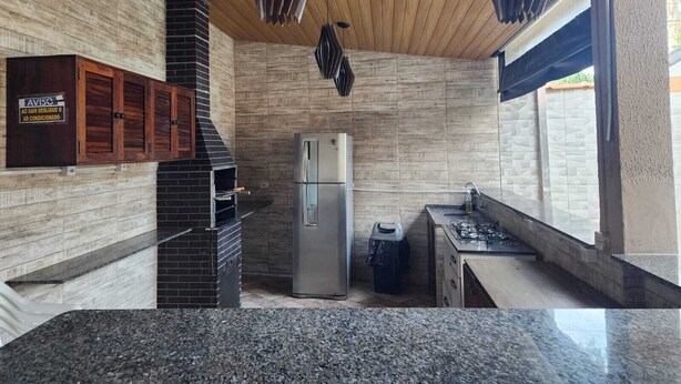A kitchen with a built-in oven, a refrigerator, and a gas stove. - House with Heated Pool - Perequê-Açu - UBATUBA - SP (Perequê-Acu Ubatuba)