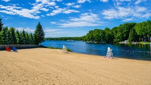 Une plage de sable avec des postes de surveillance pour les sauveteurs et un panneau indiquant la zone autorisée à la baignade.