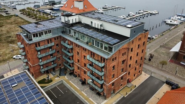 Un immeuble à plusieurs étages, doté d’une façade en briques et d’un toit plat recouvert de panneaux solaires.