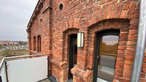 Un bâtiment en briques doté d’un balcon, d’une porte et d’une fenêtre.
