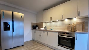 Une cuisine moderne dotée d’appareils électroménagers en acier inoxydable, de meubles blancs et d’un plan de travail en bois.