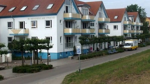 Een rij moderne, meerlaags woongebouwen met balkons en een heldere lucht.