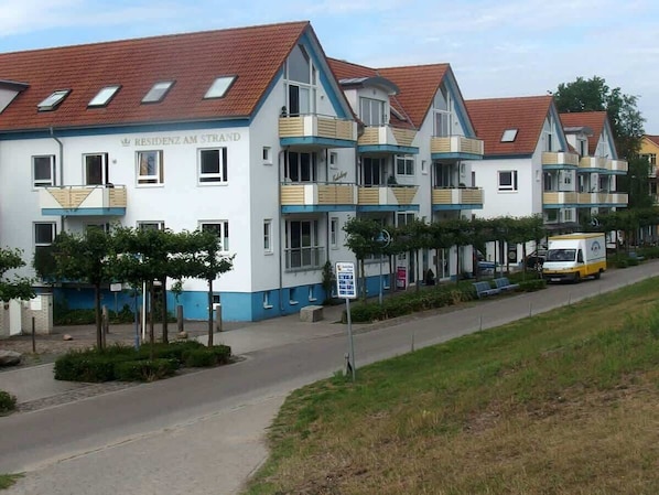 Una hilera de edificios residenciales modernos, de varios pisos, con balcones y un cielo despejado.