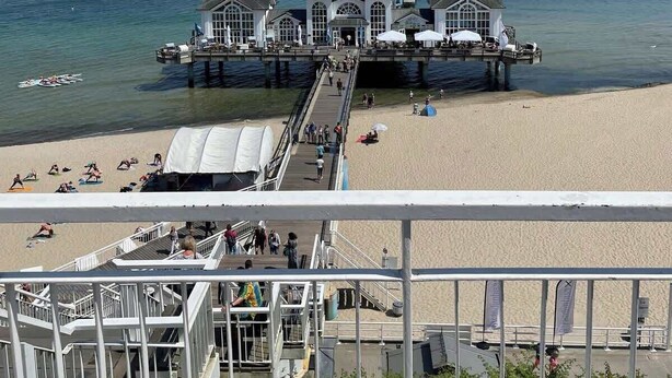 Eine Mole mit einem weißen Gebäude, einem Strand und einem strahlend blauen Himmel.