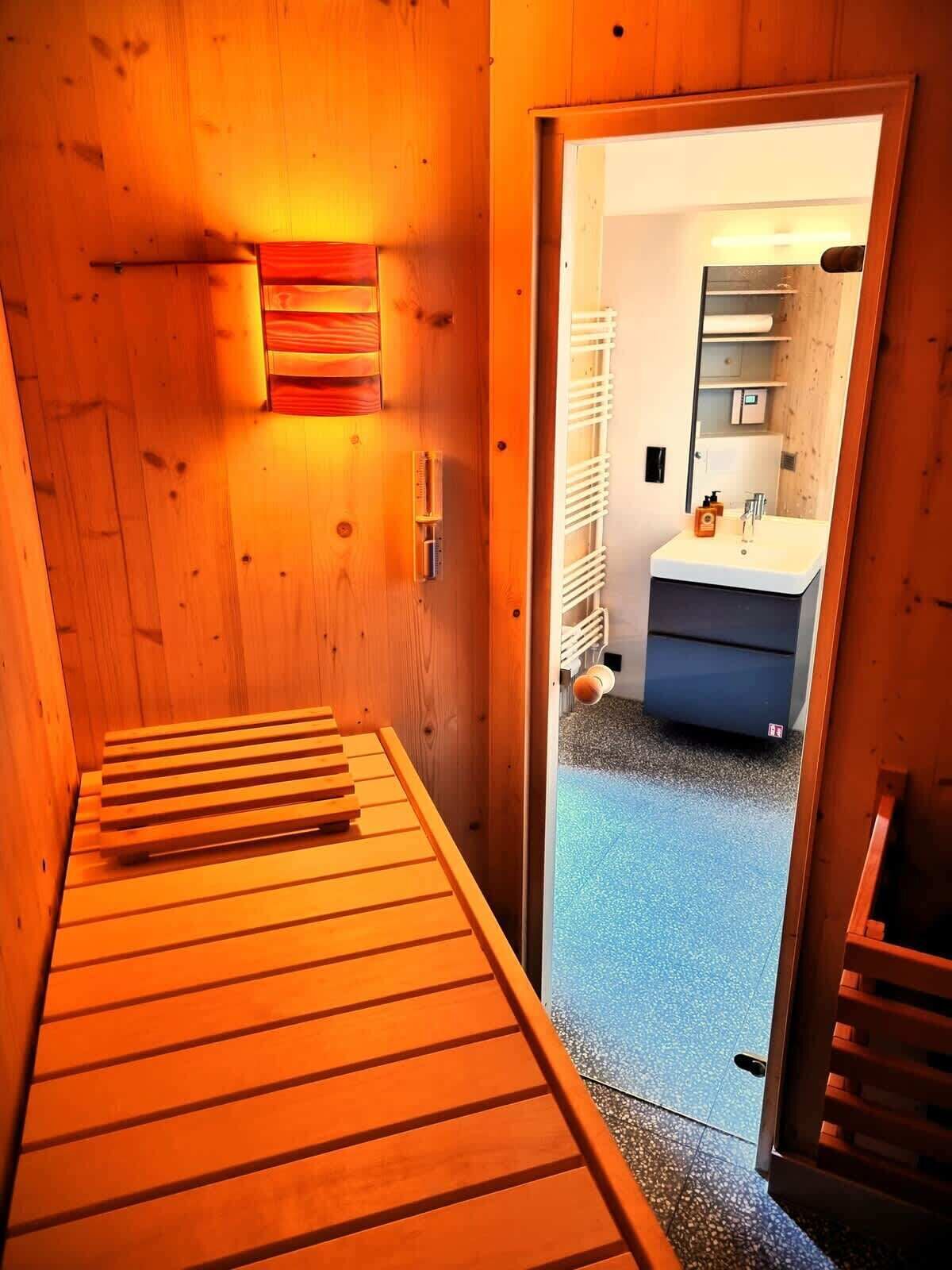 Een houten interieur met een bed, een wandheater en een badkamer die door een open deur zichtbaar is.