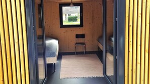 Een moderne, compacte kamer met een bed, een stoel en een kleine tafel.