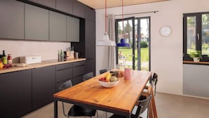 Een moderne keuken met donkere kastjes, een houten eettafel en een schaal met fruit.