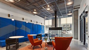 Ein moderner Lounge-Bereich mit orangefarbenen Sesseln, einem runden Tisch und einem blauen Wanddesign mit geometrischen Formen.