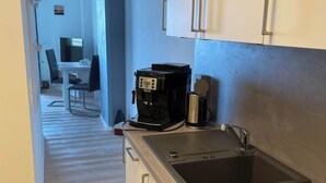 Une cuisine compacte équipée d’une cuisinière intégrée, d’une machine à café et d’un évier.