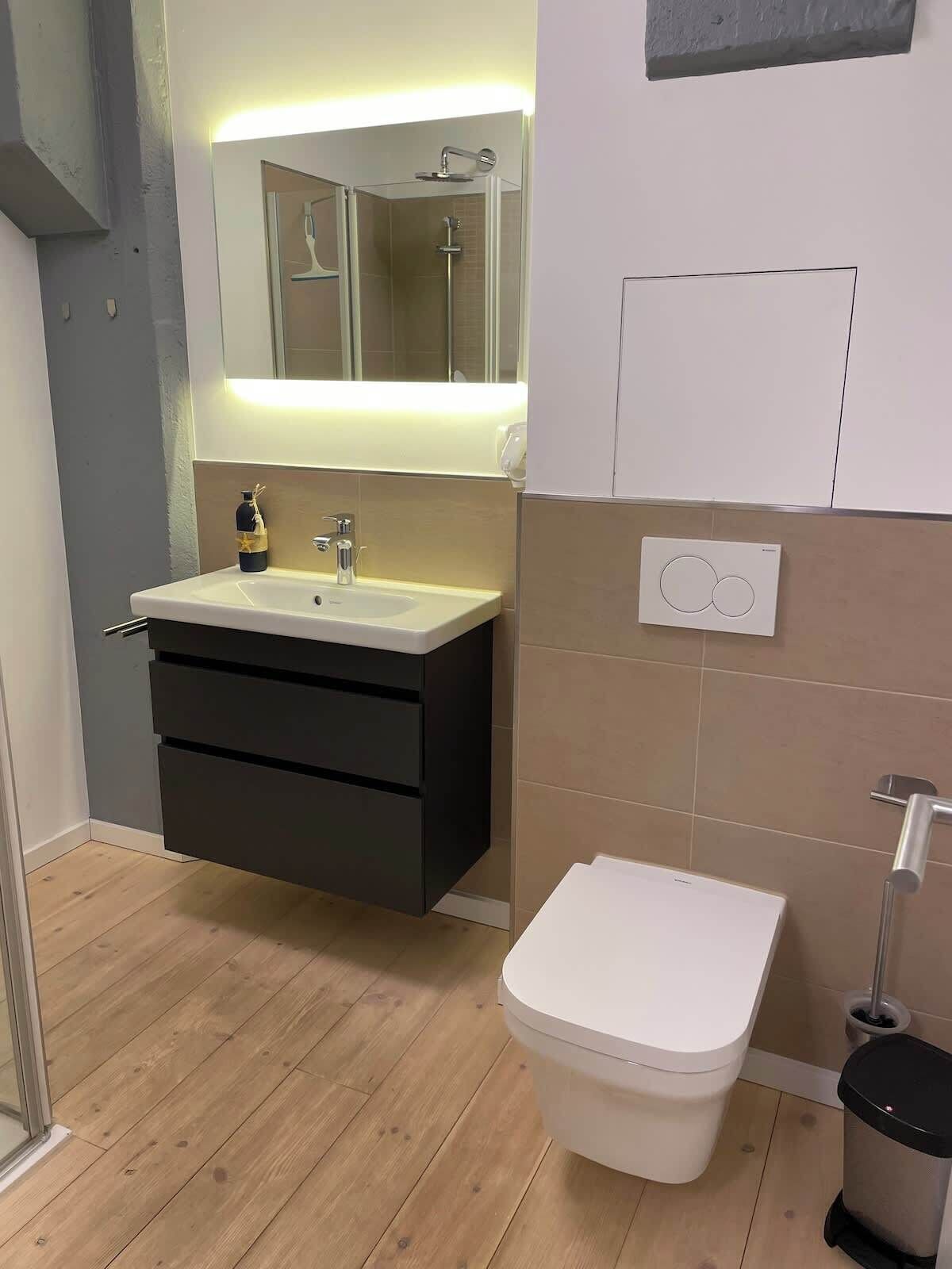 A modern bathroom with a shower, sink, and toilet.