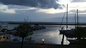 Un port de plaisance avec des bateaux amarrés, un pont en arrière-plan et un ciel nuageux.