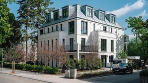 Ein modernes, zweistöckiges Gebäude mit Flachdach, großen Fenstern und einem Balkon.