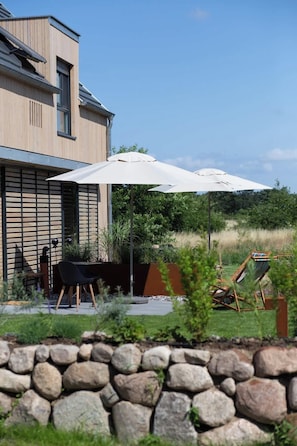 Una casa moderna con patio, mobili da esterno e un muro in pietra.