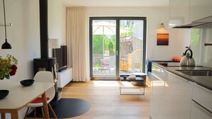 A modern kitchen with a dining area, a large sliding glass door to the outside, and a view of a patio area. - Holiday Home SandDorn 1 (Pruchten)