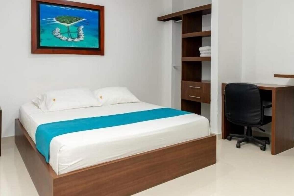 A bedroom with a bed, a desk, and a chair.
