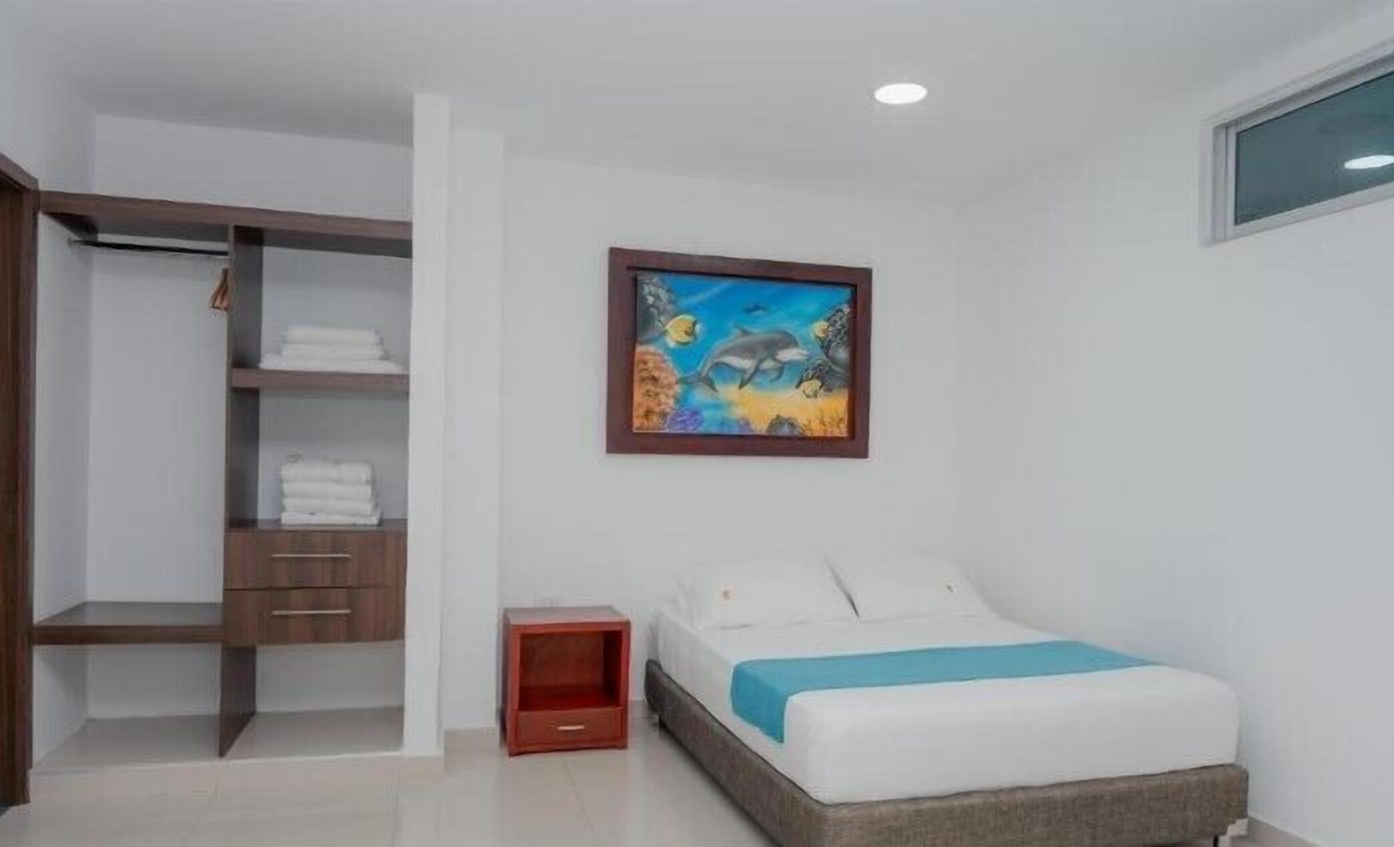 A bedroom with a bed, a nightstand, a wardrobe, and a painting of dolphins.